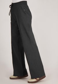 Zwarte wijde broek met een elastische tailleband en trekkoord. Beschikt over twee zijzakken en contrasterende stiksels.