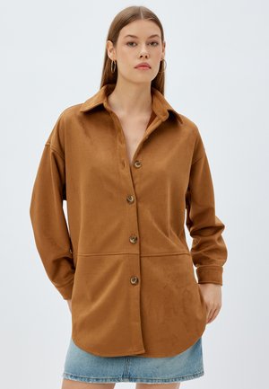 Camicia button-up marrone realizzata in tessuto morbido, con colletto, maniche lunghe e orlo curvato. Include bottoni marroni e una vestibilità rilassata.