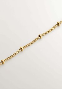Pulsera de cadena de oro con eslabones entrelazados, que presenta cuentas redondas a intervalos. Textura suave, acabado pulido y forma uniforme.