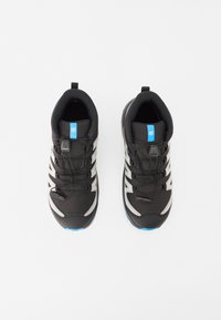 Chaussures de sport noires avec des accents argentés, tige en mesh et logo bleu. Dotées de lacets élastiques et d'une semelle texturée pour une meilleure adhérence.