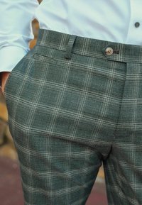 Grüne karierte Hose aus strukturiertem Stoff mit Knopfverschluss und Seitentaschen, slim fit und taillierte Passform.