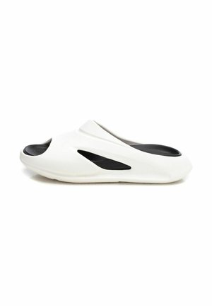 Zapato blanco sin cordones con plantilla interior negra, con diseños recortados y bordes suaves y redondeados. Fabricado en un material ligero y flexible.