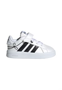 Baskets blanches Adidas avec des bandes noires, une bride en Velcro, un devant à lacets, et un motif nœud noir sur le côté, vues de profil.