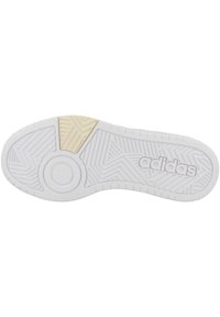 Suela de zapatilla blanca con goma texturizada, que presenta patrones de espiga y circulares. Acento dorado en el talón. Marca visible en letras en relieve.