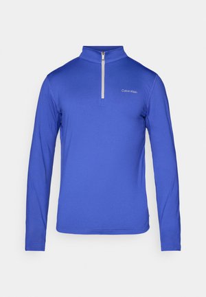 Modra dolga majica s puloverjem in pol-zadrgo, izdelana iz gladkega materiala. Ima vezeno logotip na prsih.