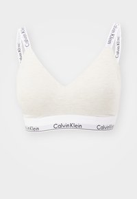 Lys grå bomulls bralette med trekantet fasong, med hvite stropper og en merkevare elastikk med teksten "Calvin Klein".