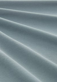 Tissu bleu clair avec une texture lisse, présentant des motifs ribbed subtils et des plis doux et fluides.