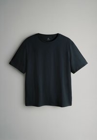 Juoda trumpomis rankovėmis laisvo silueto marškinėliai. Pagaminti iš lygios medvilnės, su apvalia kaklo iškirpte, be matomų raštų ar akcentų.