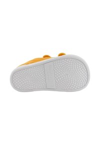 Vista inferior de un zapato de ante amarillo con una suela de goma blanca texturizada que presenta un patrón de diamantes y bordes suaves. Marcado "Blanditos by Cirios."