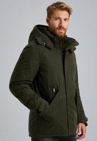 Tmavě zelená izolační bunda s kapucí, vybavená zipovými kapsami a patentkami, hladká textura a přiléhavý střih.