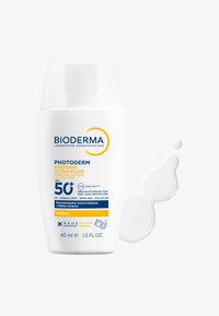 Flacon cylindrique blanc de Bioderma Photoderm, 40 mL, avec une étiquette jaune et bleue, distribuant un fluide solaire crémeux blanc.