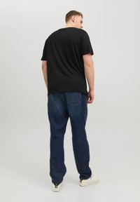Black short-sleeve t-shirt, relaxed fit, paired with blue denim jeans. Simple design, cotton material, features a back view with plain texture.