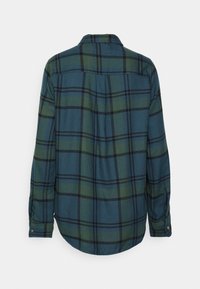 Koszula w kratę w niebiesko-zielonej kolorystyce z czarnymi i ciemnozielonymi wzorami. Długie rękawy, mankiety na guziki oraz wygięty dół.