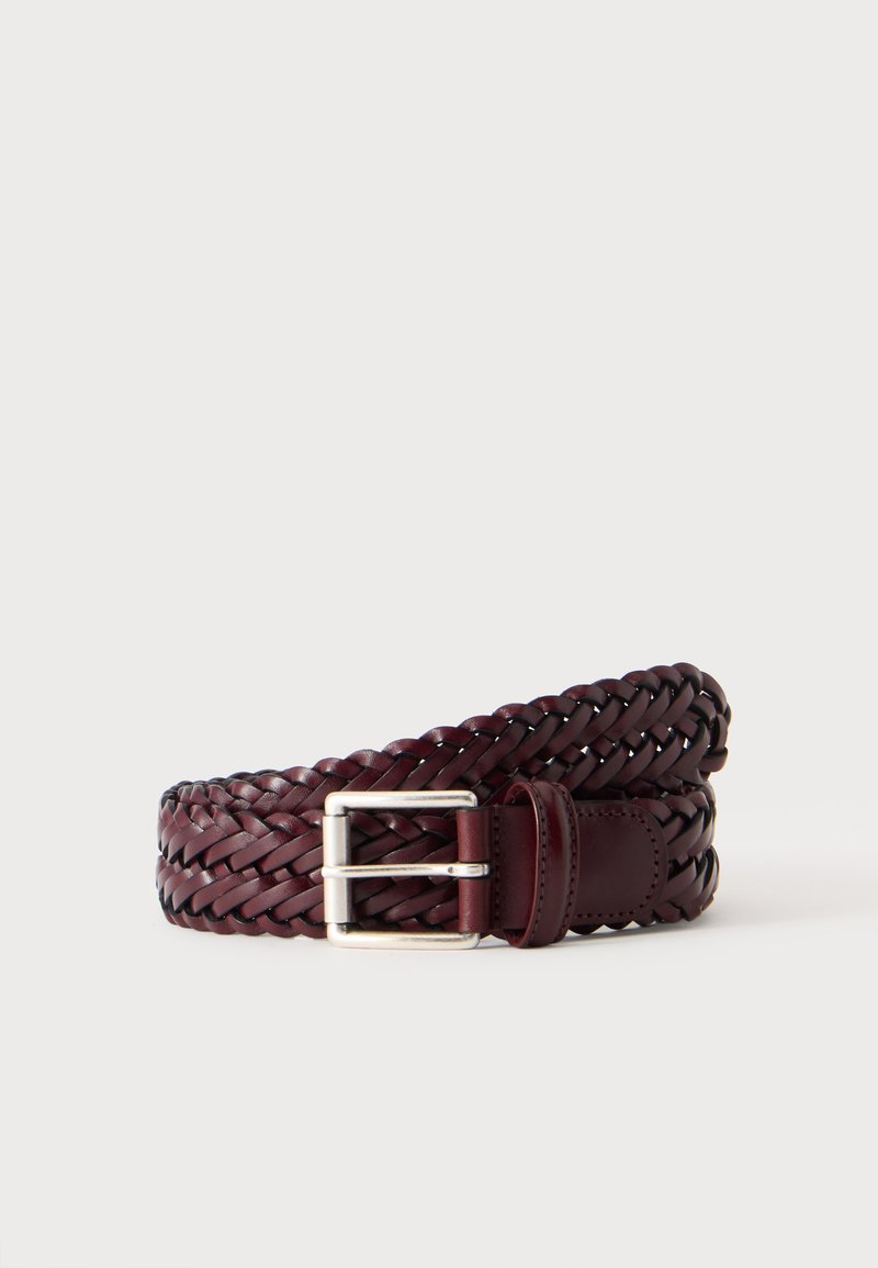 Ceinture en cuir marron foncé tressée avec boucle rectangulaire argentée, enroulée sur un fond clair.