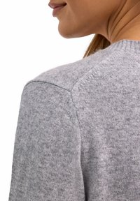 Grauer Strickpullover mit rundem Halsausschnitt und gerippten Details am Kragen und den Schultern, der einen weichen, strukturierten Stoff zeigt.