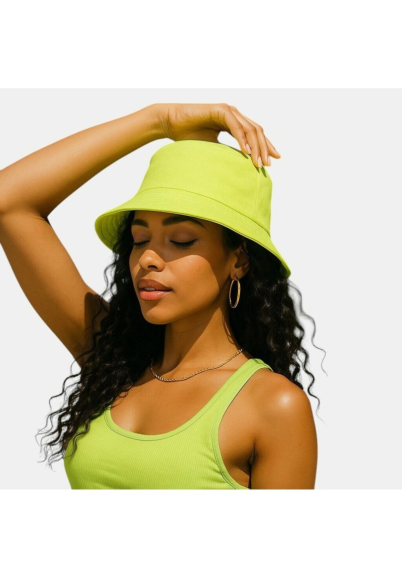 Cappello a secchiello verde brillante con una consistenza morbida e tesa larga, indossato con una canottiera verde abbinata. Capelli mossi parzialmente visibili.