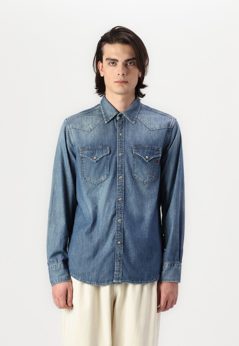 Camicia di jeans a maniche lunghe di color blu chiaro, con yoke a punta, due tasche sul petto e chiusura con bottoni, realizzata in morbido cotone.