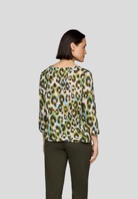 Transluzente Bluse mit einem Tierdruckdesign in Grün, Blau und Braun. Mit Dreiviertelärmeln und rundem Ausschnitt.