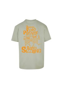 Lys grøn bomulds t-shirt med orange grafisk tryk af dansende ananas og tekst: "Dansende Funky Ananas Sommer Sizzlende."