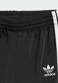 Black athletic shorts made of smooth fabric, featuring a stretchy waistband and white side stripes. Includes a small white logo.