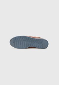 Semelle de chaussure en cuir marron avec un fond en caoutchouc bleu. Les caractéristiques incluent des rainures horizontales et un logo circulaire au niveau du talon.