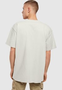 Overdimensioneret lysegrå bomulds-t-shirt, korte ærmer, rund halsudskæring, afslappet pasform, ensartet tekstur, ingen synlige mønstre eller hardware.