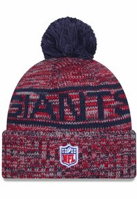 Rote und graue Strickmütze mit umgeschlagenem Saum, mit "GIANTS" in marineblau, gekrönt mit einem marineblauen Pom-Pom und einem NFL-Logo-Patch.