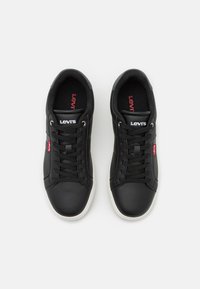 Schwarze Ledersneaker mit glatter Textur, weißen Gummisohlen, Schnürsystem und rotem Levi's-Label an der Seite und Zunge.
