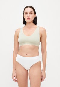 Sutiã desportivo verde claro com textura suave e design de decote em V profundo, combinado com roupa interior branca de cintura alta com uma faixa suave.