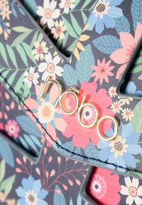 Borsa a tracolla con motivo floreale su uno sfondo scuro, caratterizzata da fiori rosa, blu e verdi, con un accento in oro del logo. Realizzata in materiale testurizzato.