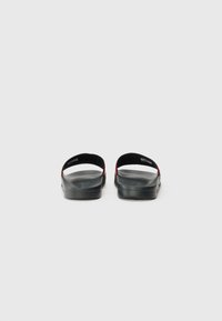 Black rubber sandals with a textured footbed and red accents; open back design with cushioned straps for comfort.