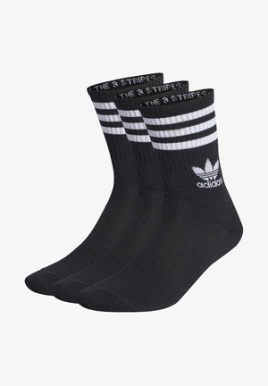 Calcetines deportivos negros con tres rayas blancas horizontales en la parte superior. Incluyen una textura acanalada y el logo de adidas en blanco.