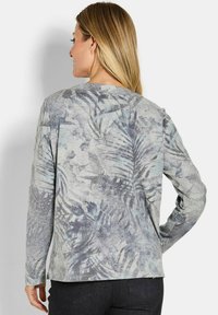 Langsleeve top in lichtgrijze stof met een palmbladvorm in donkergrijze en blauwe tinten. Soepele textuur, ronde halslijn, normale pasvorm.