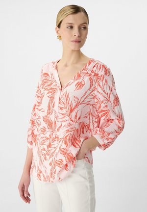 Lichtroze blouse met een V-hals, voorzien van een gedurfde rode botanische print. Losse pasvorm, driekwartmouwen en een zachte, lichte textuur.