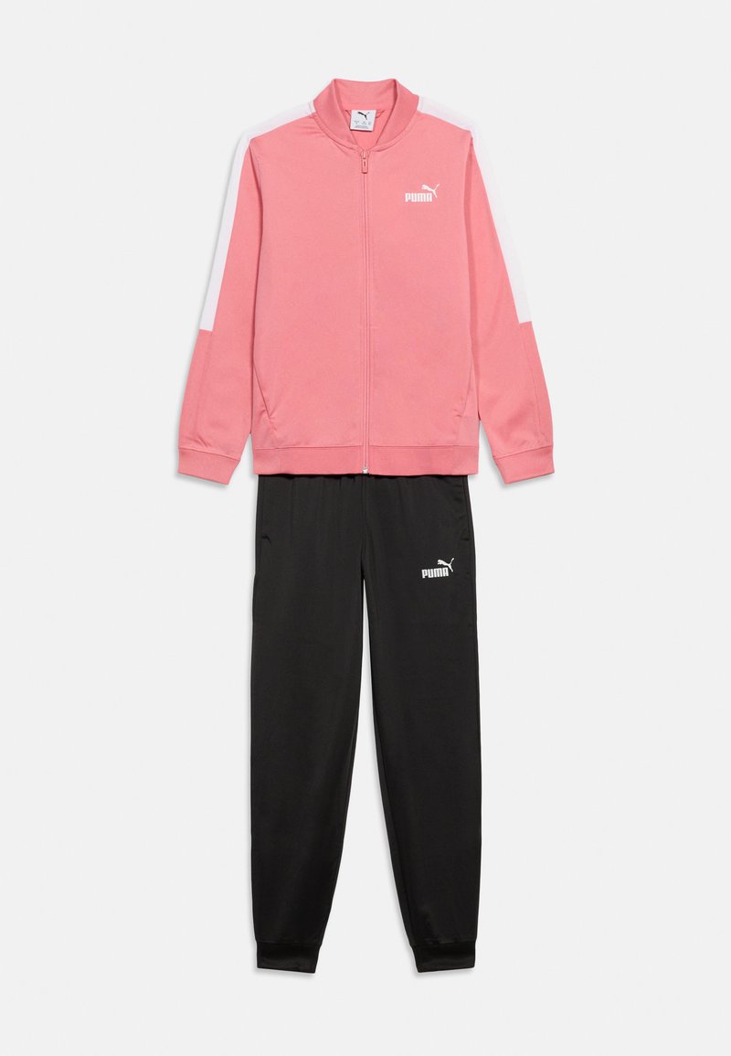 Ροζ φόρμα με φερμουάρ και λευκές ρίγες στα μανίκια και μαύρο παντελόνι φόρμας, και τα δύο με λευκά λογότυπα Puma.