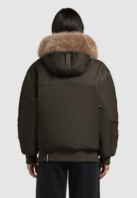Jachetă tip puffer în verde măsliniu închis, cu glugă căptușită cu blană, având o croială lejeră și manșete ribbate, evidențiind un finisaj neted și lucios.