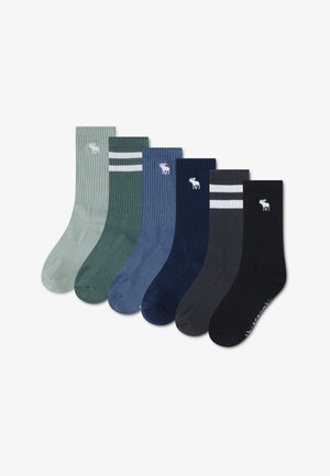 Six paires de chaussettes côtelées montantes en vert, vert foncé avec des rayures blanches, bleu, marine, gris foncé avec des rayures blanches et noir, chacune avec un logo élan blanc.