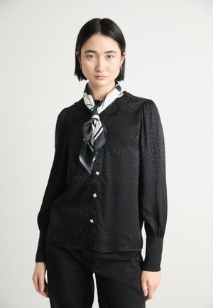 Zwarte satijnen blouse met een gemêleerd luipaardpatroon, lange mouwen, kanten kraag en decoratieve zilveren knopen, gecombineerd met een zwart-wit sjaal.
