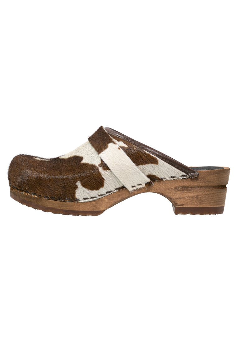 Bruine en witte koeienvlek clogs met een houten zool. Heeft een soepele leren band en een textuur die lijkt op bont bovenwerk. Zijaanzicht.