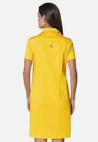 Gelbes Kurzarmkleid mit Kragen, das einen Rückenvent und Knopfdetails aufweist. Hergestellt aus glatten Stoff mit einer schmeichelhaften Silhouette.
