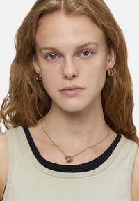 Guldtonet smykke med hoops øreringe og en vedhængs halskæde. Øreringene har et snoet design, og halskæden har en kæde med en sløjfe accent.