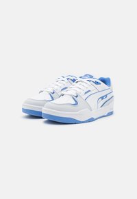 Baskets Puma blanches et bleu clair avec design à lacets, col rembourré et semelle épaisse, vues de côté avant sur fond blanc.