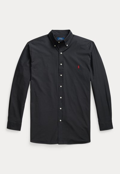 Musta pitkähihaisen napillinen paita, jossa napillinen kaulus ja pieni punainen brodeerattu Polo Ralph Lauren logo vasemmassa rinnassa.