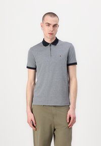 Sivá polo tričko s námorníckym golierom a krátkymi rukávmi. Obsahuje zips na prednej strane a malé logo na hrudi. Vyrobené z mäkkej zmesi bavlny.