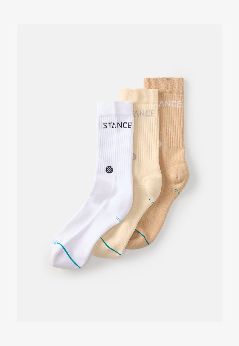 Three pairs of crew socks in white, light beige, and tan, featuring ribbed texture and the brand logo "STANCE" in contrasting colors.