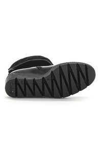 Chaussures noires avec une semelle en caoutchouc texturé présentant des motifs en zigzag, fabriquées en cuir et en tissu, arborant un design low-cut.