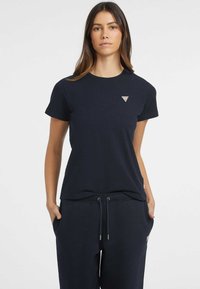 Navy blue short-sleeve t-shirt made from cotton. Features a triangular logo patch on the chest and a round neckline. Smooth texture.