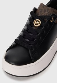 Svart lær sneakers med tykk hvit såle, svarte lisser og brun logo-mønstret tunge med et gull MK-emblem.