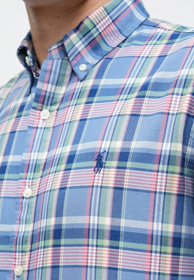 Κοντομάνικο καρό πουκάμισο σε μπλε, πράσινους και ροζ τόνους. Διαθέτει γιακά με κουμπιά και κεντημένο λογότυπο στο στήθος. Υλικό μείγμα βαμβακιού.