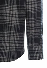 Klassisk flannel skjorteærme i et sort og gråt ternet mønster. Har en knapmanchet med en glat tekstur og en buet kant.